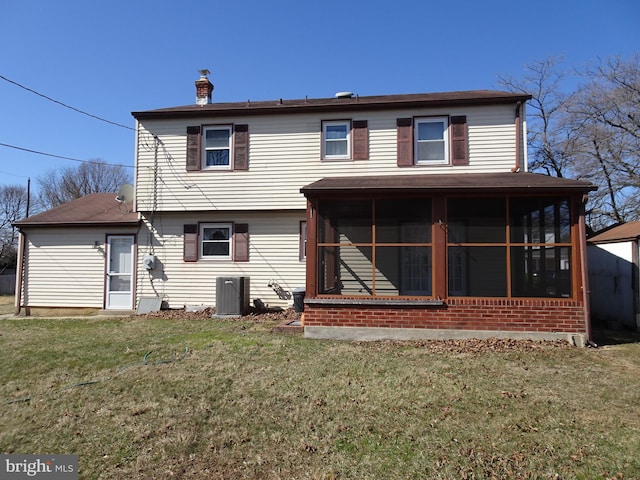 rear view of house with cooling unit, a lawn, a sunroom, and a chimney