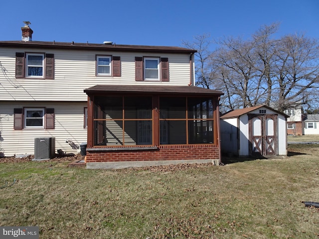 back of property with an outbuilding, a sunroom, a lawn, and a shed