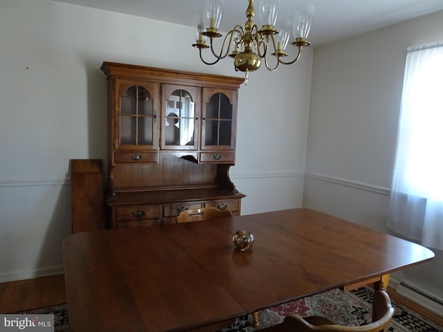 dining space with a notable chandelier, a baseboard heating unit, and wood finished floors