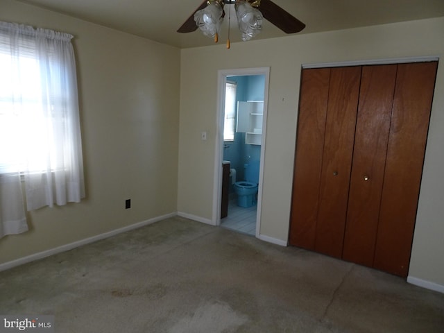 unfurnished bedroom featuring a ceiling fan, ensuite bath, a closet, carpet, and baseboards