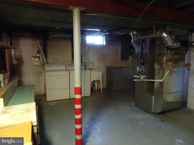 below grade area featuring a sink, heating unit, and washer and clothes dryer