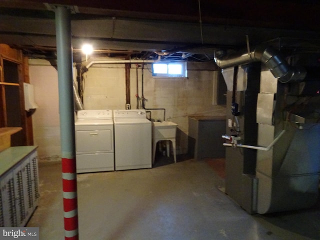 basement with a sink, heating unit, and separate washer and dryer