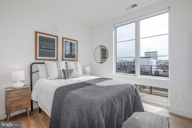 bedroom featuring baseboards, visible vents, and wood finished floors