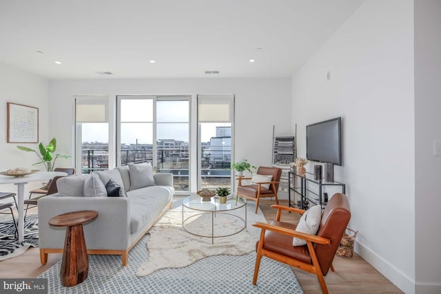 living area with baseboards, visible vents, wood finished floors, and recessed lighting