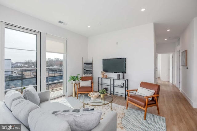 living room featuring light wood-style flooring, visible vents, baseboards, and recessed lighting