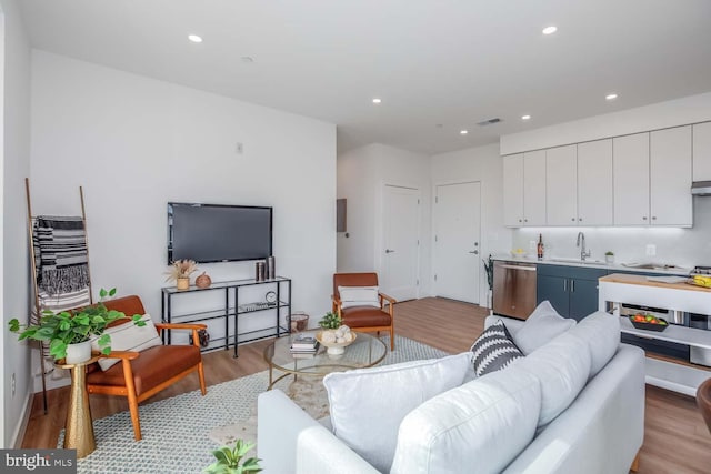 living room with light wood-type flooring, visible vents, and recessed lighting