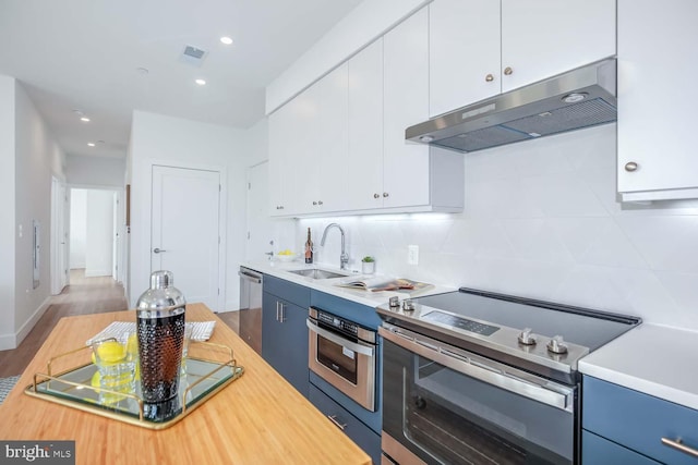 kitchen featuring under cabinet range hood, a sink, visible vents, appliances with stainless steel finishes, and backsplash