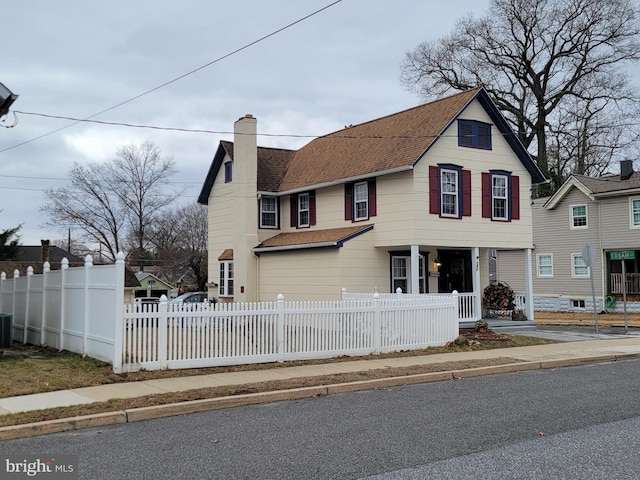 view of front of house with roof with shingles, a fenced front yard, and a chimney