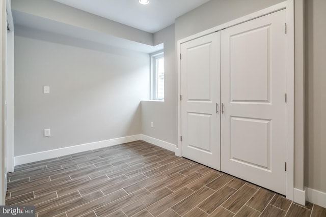 unfurnished bedroom with wood finish floors, a closet, and baseboards