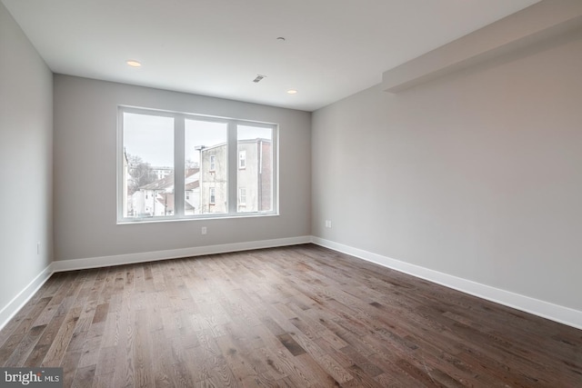 unfurnished room featuring recessed lighting, wood finished floors, and baseboards