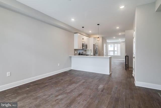 kitchen featuring stainless steel appliances, light countertops, dark wood-type flooring, white cabinetry, and a peninsula