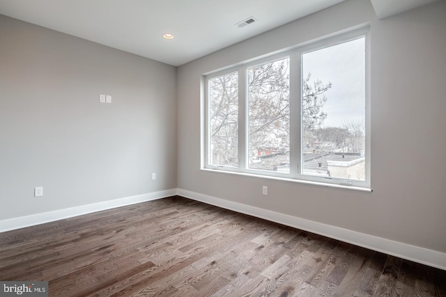 spare room featuring dark wood-style floors, recessed lighting, visible vents, and baseboards