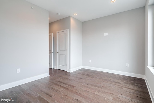 spare room featuring recessed lighting, wood finished floors, and baseboards