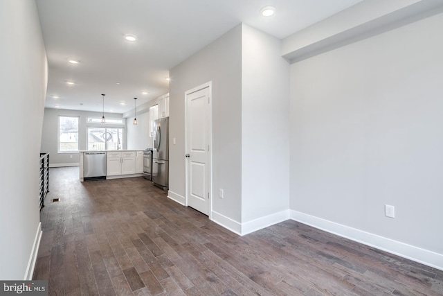 interior space featuring stainless steel appliances, white cabinetry, baseboards, light countertops, and dark wood finished floors