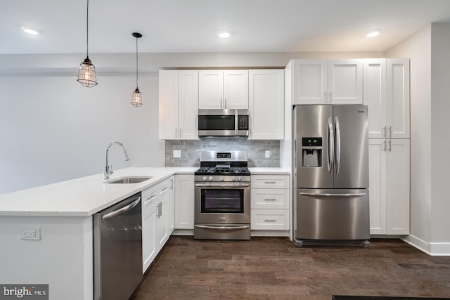 kitchen with stainless steel appliances, a peninsula, dark wood-style flooring, a sink, and backsplash