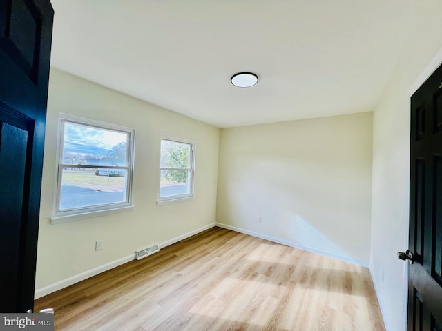 spare room with visible vents, baseboards, and wood finished floors