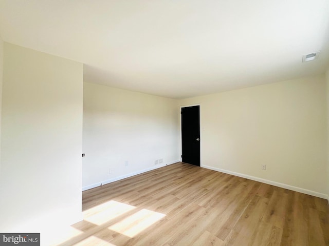 unfurnished room with light wood finished floors, baseboards, and visible vents