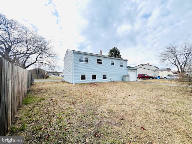 rear view of house with a garage, fence, and a chimney