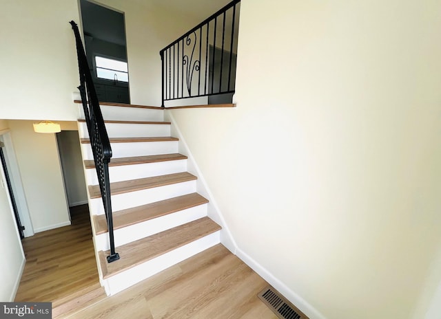 stairway with baseboards, visible vents, and wood finished floors