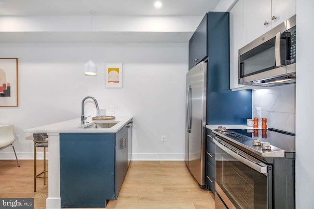 kitchen featuring blue cabinets, stainless steel appliances, a peninsula, a sink, and a kitchen breakfast bar