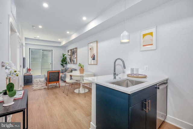 kitchen featuring light countertops, light wood-style floors, a sink, blue cabinets, and dishwasher