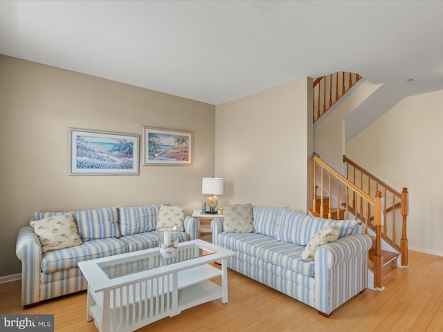 living area with light wood-style flooring, stairway, and baseboards