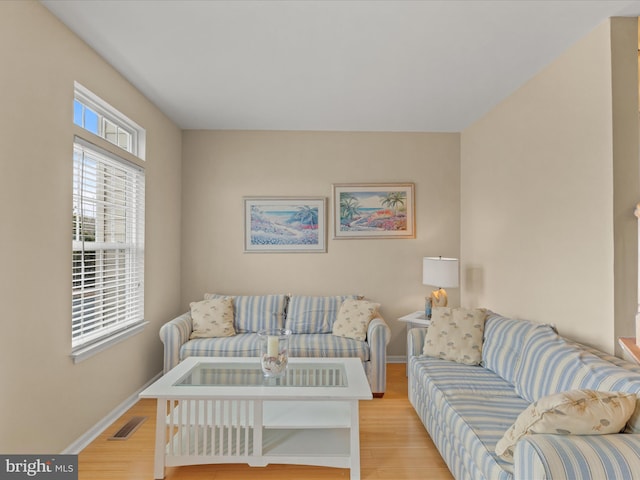 living room featuring light wood-style flooring, visible vents, and baseboards