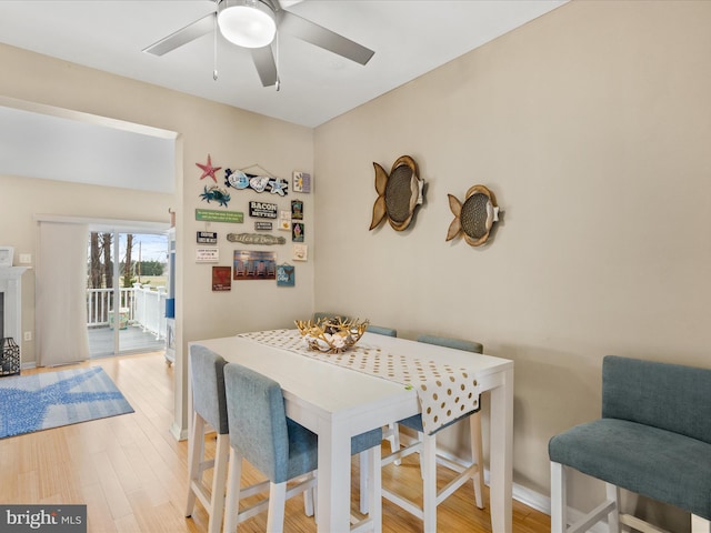 dining room with a ceiling fan, light wood-type flooring, and baseboards