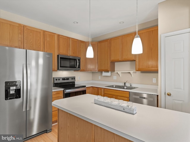 kitchen featuring appliances with stainless steel finishes, pendant lighting, a sink, and light countertops