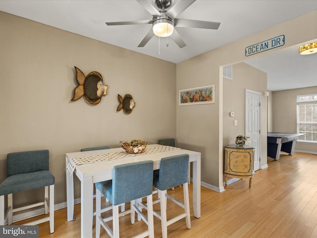 dining space featuring light wood-style flooring, a ceiling fan, visible vents, and baseboards