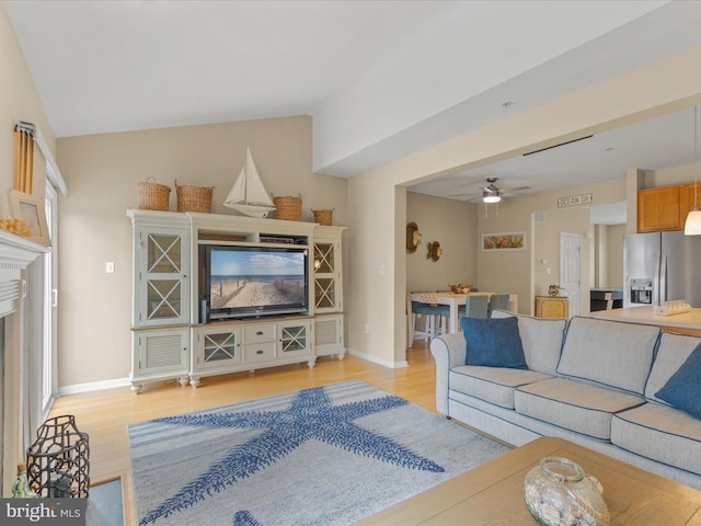 living room featuring lofted ceiling, light wood-type flooring, a fireplace, and baseboards