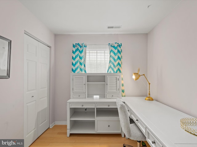 office space with built in desk and light wood-style flooring