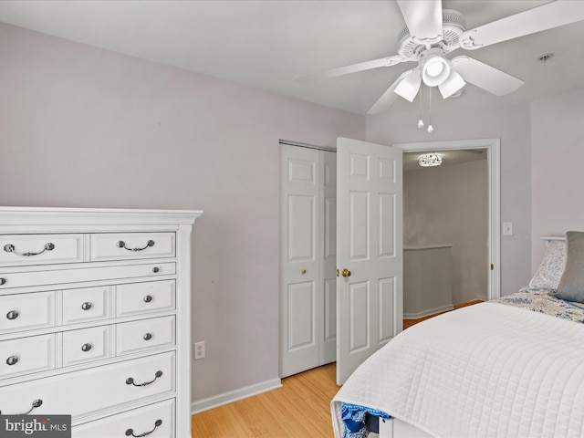 bedroom featuring a ceiling fan, a closet, light wood-style flooring, and baseboards