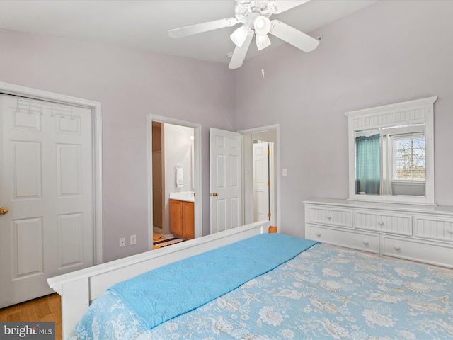 bedroom featuring a ceiling fan, lofted ceiling, ensuite bath, and wood finished floors