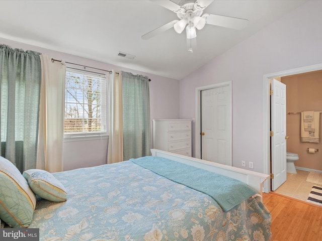 bedroom featuring visible vents, connected bathroom, ceiling fan, wood finished floors, and vaulted ceiling