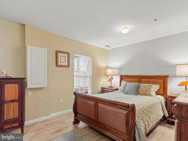 bedroom featuring visible vents, light wood-style flooring, and baseboards