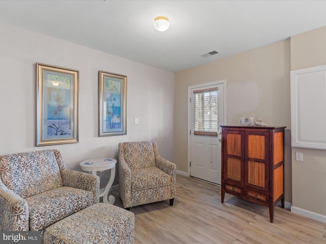 living area featuring light wood-type flooring, visible vents, and baseboards