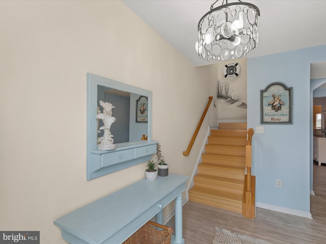 stairway with an inviting chandelier, baseboards, and wood finished floors