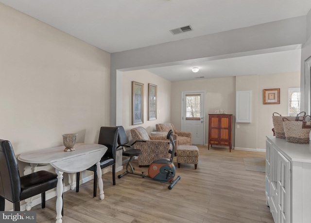 living area with light wood-type flooring, a healthy amount of sunlight, and visible vents