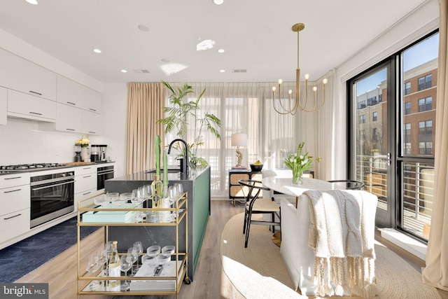 kitchen featuring a sink, appliances with stainless steel finishes, light wood-style floors, white cabinetry, and modern cabinets