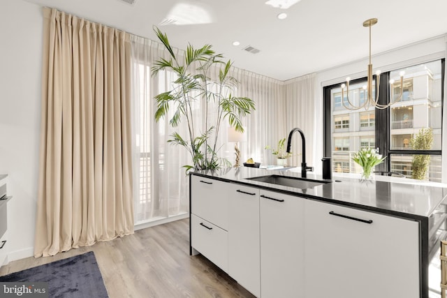 1500 Harry Thomas Way NE Unit 501, Washington, DC 20002 - kitchen featuring visible vents, a sink, dark countertops, light wood-style floors, and white cabinets