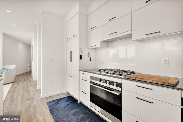 1500 Harry Thomas Way NE Unit 501, Washington, DC 20002 - kitchen with light wood finished floors, baseboards, under cabinet range hood, white cabinets, and stainless steel appliances