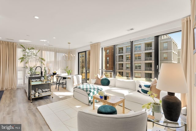 living area with a chandelier, visible vents, recessed lighting, and wood finished floors