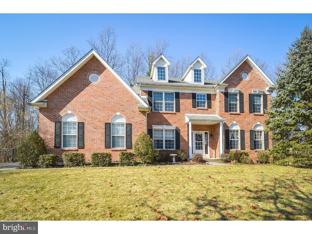 colonial house with a front yard and brick siding