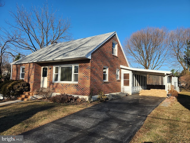 view of side of home featuring a yard, aphalt driveway, an attached carport, and brick siding