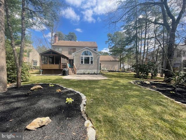 view of front of property featuring a front yard, a sunroom, and a chimney