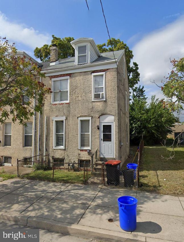 traditional style home featuring a fenced front yard, stucco siding, a chimney, and entry steps