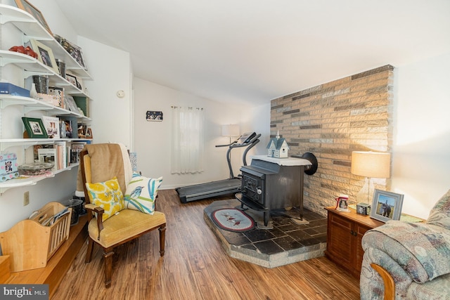 living area featuring lofted ceiling, a wood stove, and wood finished floors