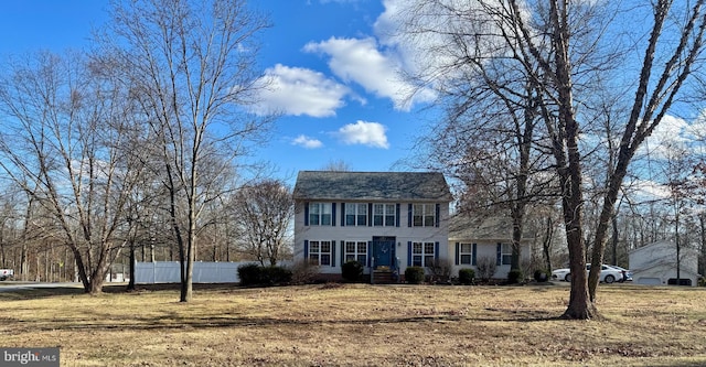 colonial home featuring fence and a front lawn