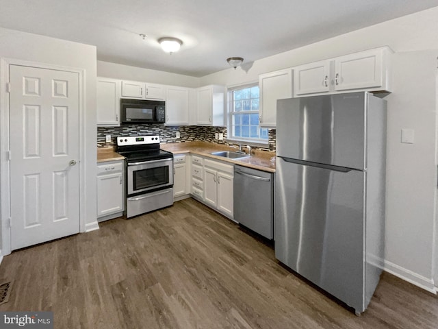 kitchen featuring dark wood-style flooring, a sink, white cabinets, appliances with stainless steel finishes, and tasteful backsplash